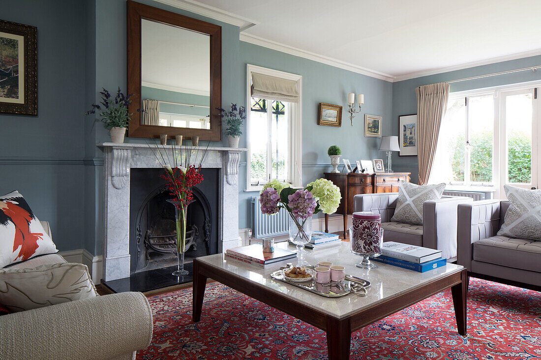 Teatray auf einem marmorüberzogenen Couchtisch mit rot gemustertem Teppich im Wohnzimmer in Berkshire, England, UK