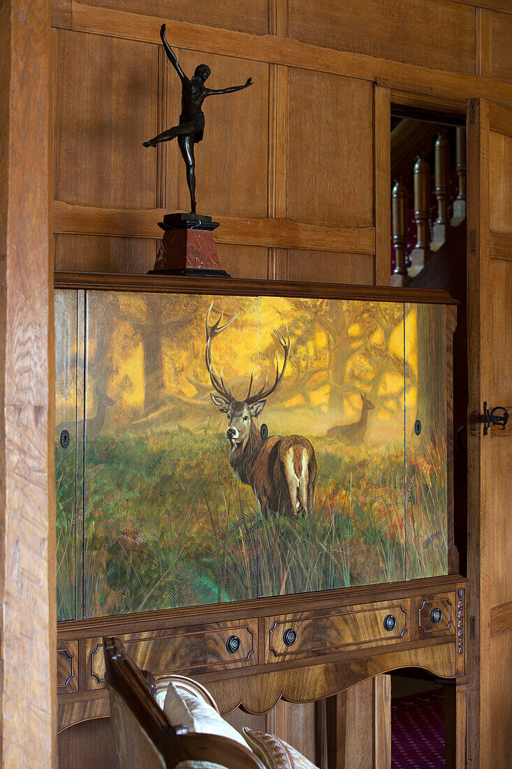 Figurine of ballerina on antique sideboard in wood panelled living room of London home, UK