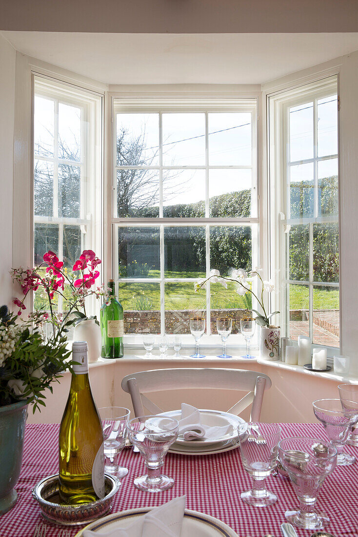 Weißer Wein und Gläser auf roter Gingham-Tischdecke am Erkerfenster von Camber cottage East Sussex England UK