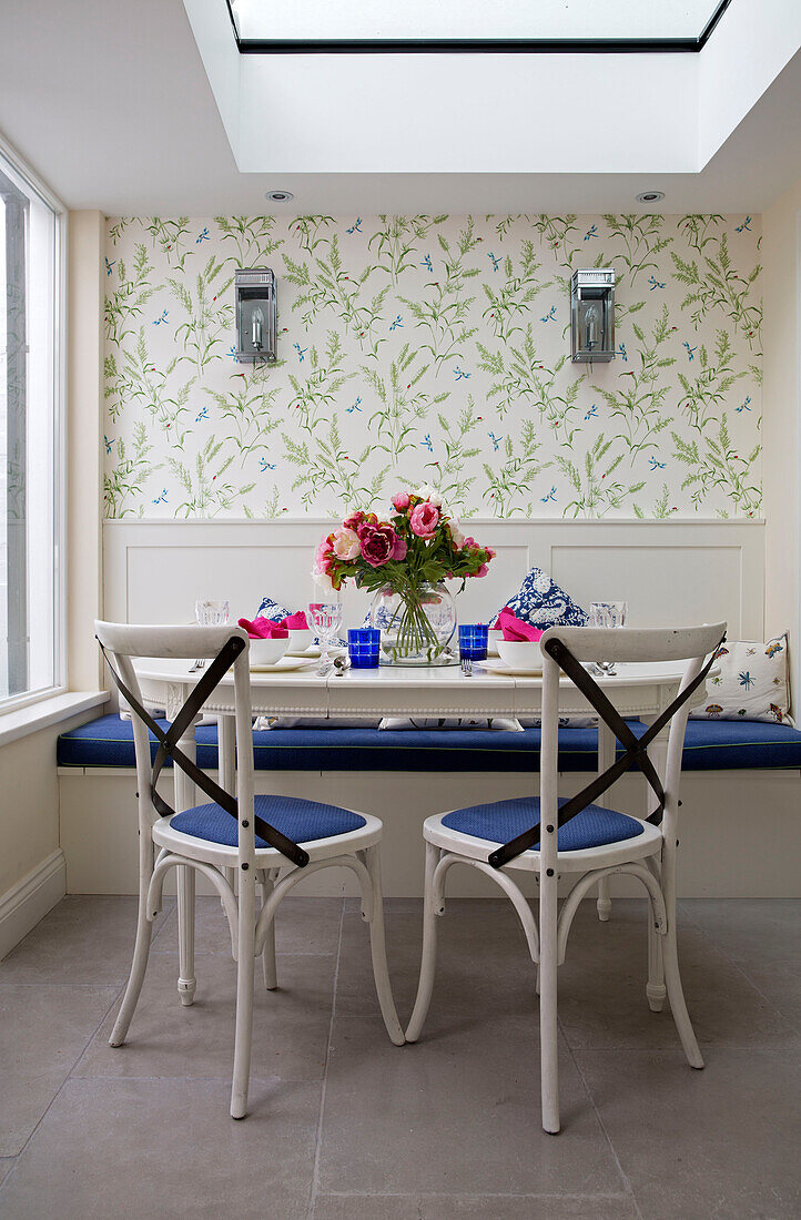 Cut flowers on kitchen table with blue seated chairs in London townhouse, England, UK