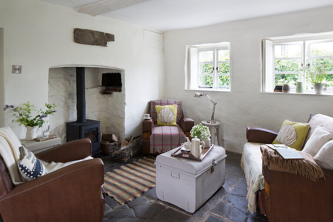 Holzofen mit dreiteiliger Sitzgarnitur und upgecycelter Reisetruhe in einem Cottage in Presteigne, Wales, Vereinigtes Königreich