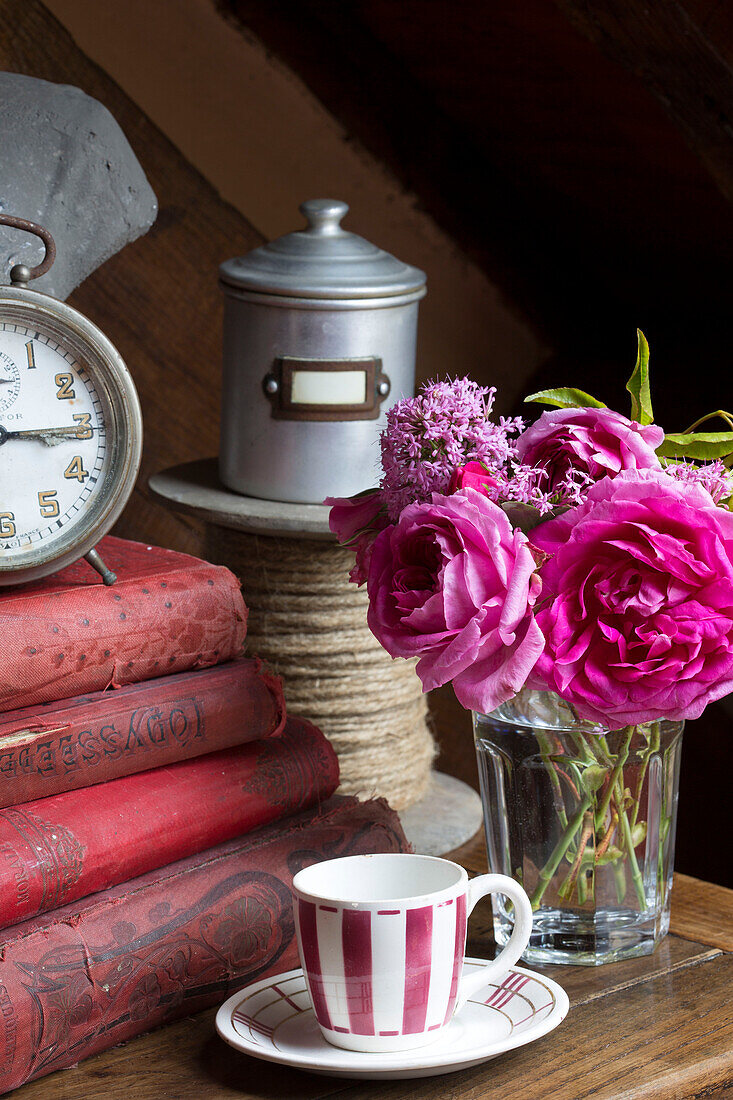 Pink roses with hard backed books and reel of rope in French farmhouse