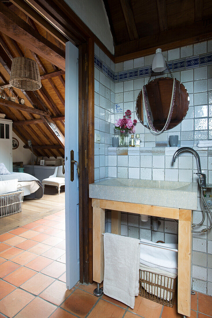 Circular mirror above wash basin in ensuite bathroom of French farmhouse bedroom