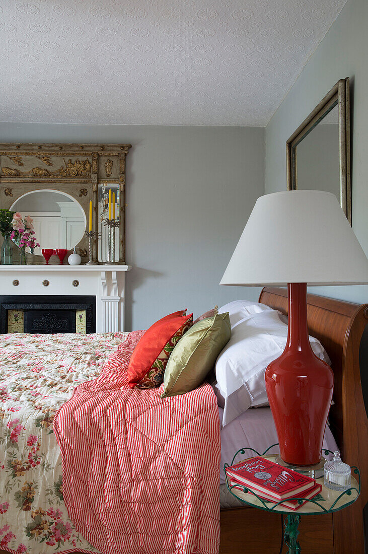 Red lamp with white shade at bedside in UK home