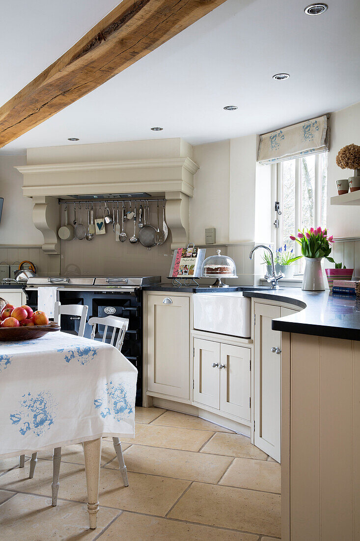 Curved white fitted kitchen with utensil rail above oven in Suffolk farm building,  England,  UK