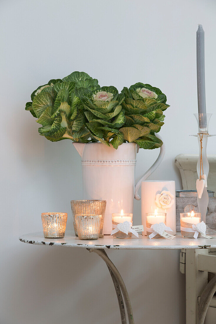 Green flowers in white jug with lit candles in Hertfordshire home,  England,  UK