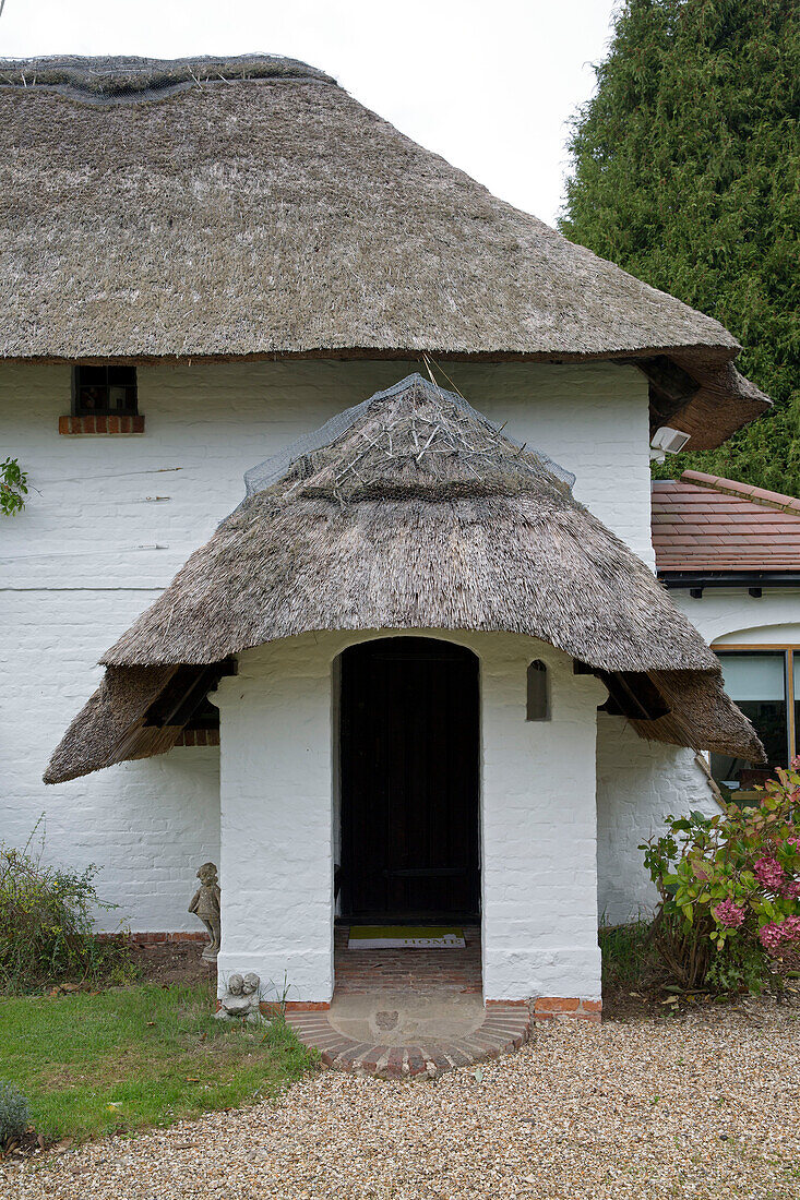 Weiß getünchte Veranda eines freistehenden reetgedeckten Hauses in Sussex, England, UK