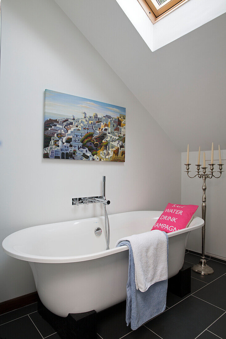 Artwork canvas above freestanding bath with candelabra in Sussex cottage bathroom   England   UK