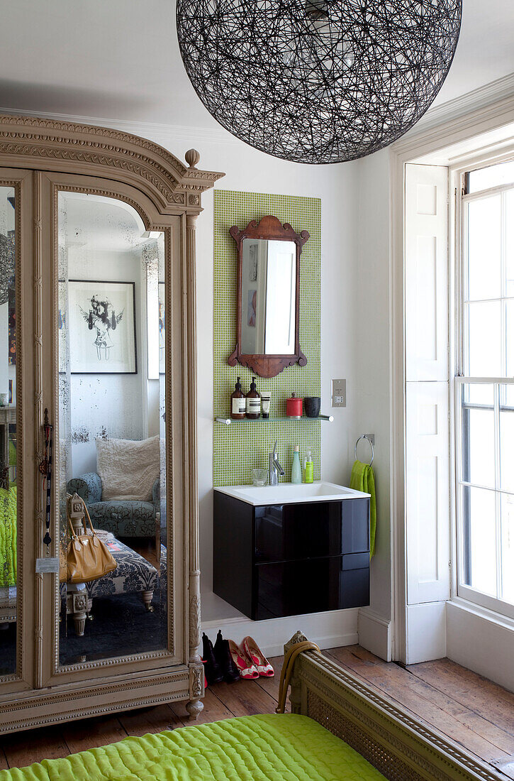 Black washbasin and mirrored wardrobe in bedroom of London townhouse, England, UK