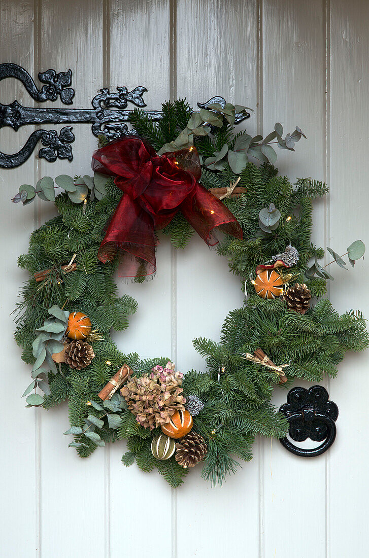 Dried oranges and pinecones in Christmas wreath with red ribbon on Lymington front door  Hampshire  UK