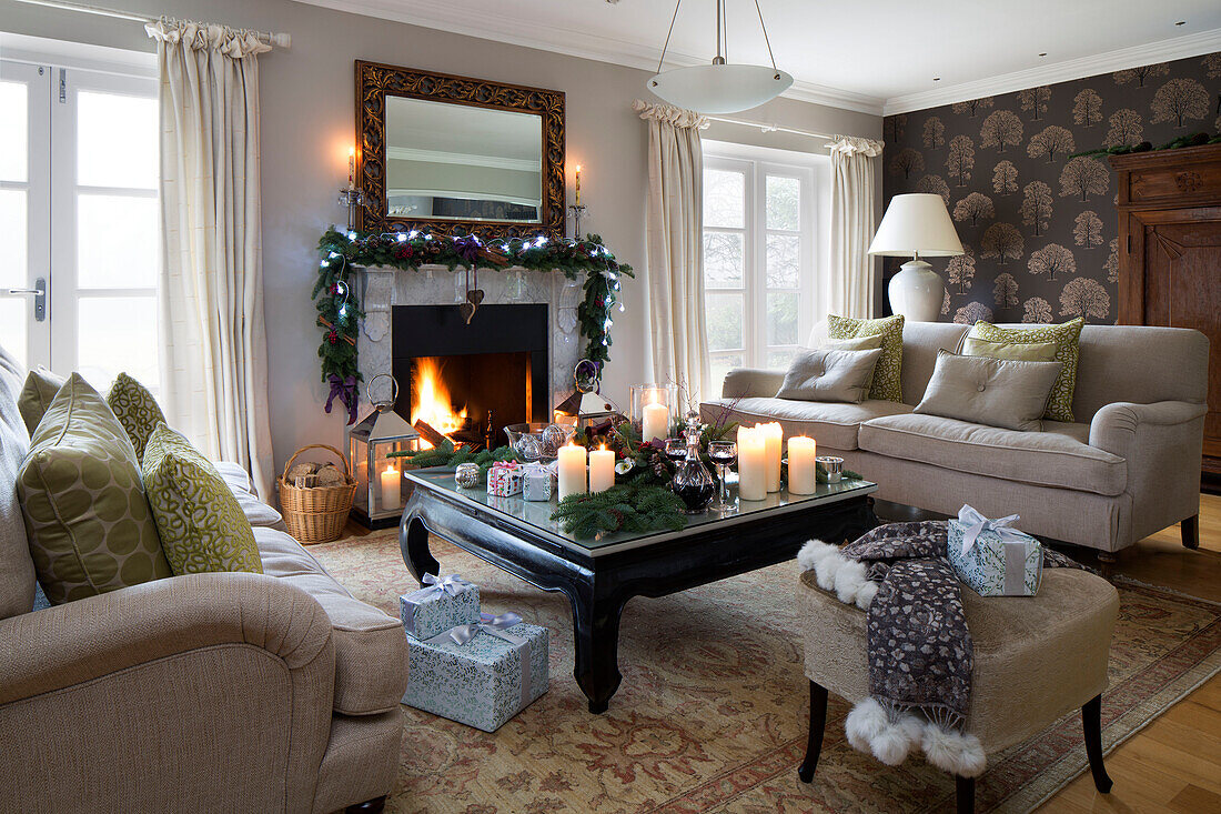 Weihnachtsgirlande mit Lichterketten über dem beleuchteten Feuer im Wohnzimmer eines Hauses in Chobham, Surrey, England, UK