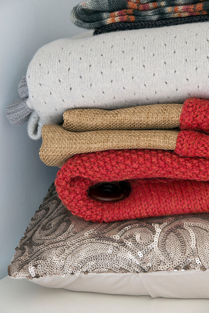 Folded blankets and sequinned cushion in London home,  England,  UK