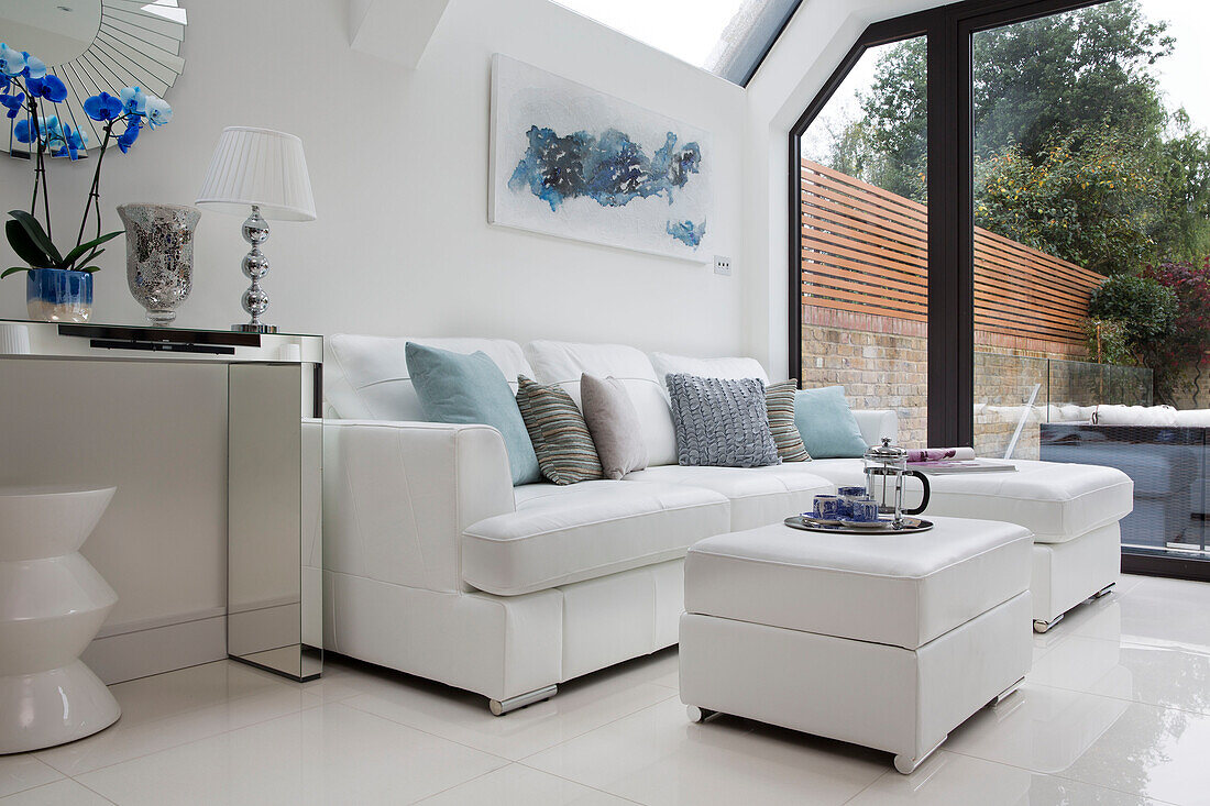 White leather sofa with ottoman footstools and mirrored console in contemporary London home   UK