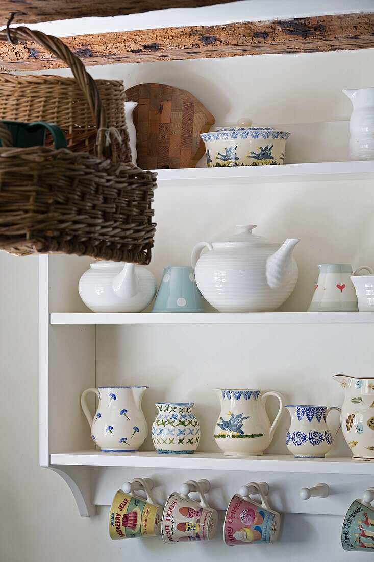 Crockery on shelves with baskets hanging in UK farmhouse kitchen