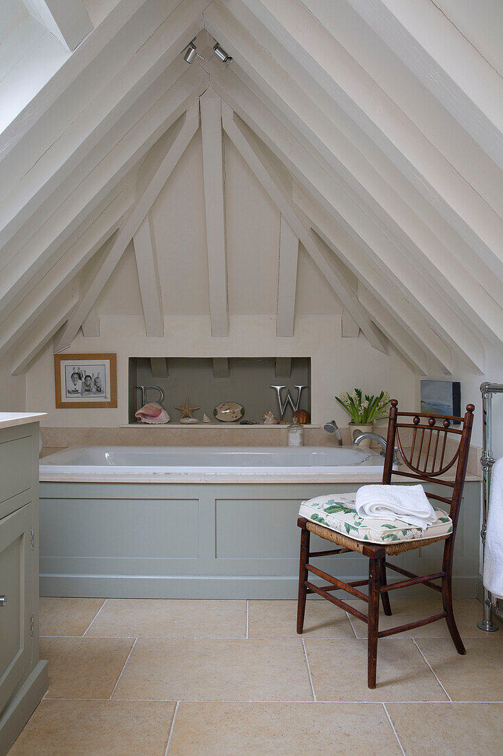 Wooden chair with seat cushion in attic bathroom of UK farmhouse