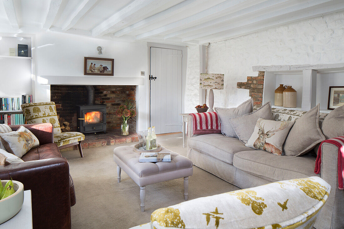 Lit wood burning stove in whitewashed living room with low painted ceiling,  London home,  England,  UK