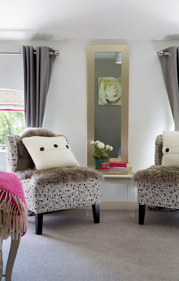 Pair of matching chairs with wool cushions and fur throws in Sandhurst bedroom  Kent  England  UK