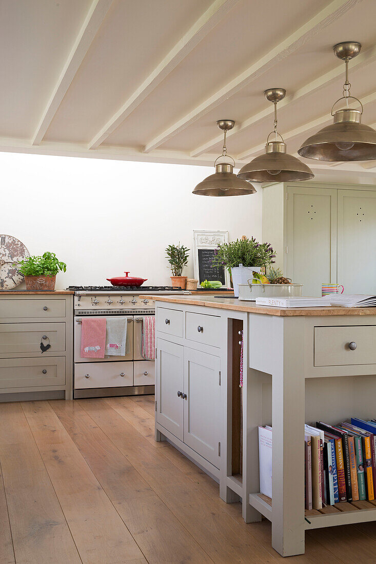 Brass pendant lights hang above kitchen island in East Dean farmhouse  West Sussex  UK