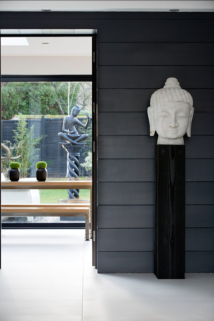 Buddha's head on plinth in zen styled interior of London home,  England,  UK