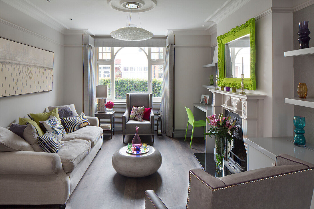 Limonengrüner Spiegelrahmen über dem Kamin mit Lilien und Marmor-Couchtisch in einem modernen Londoner Haus, England, UK