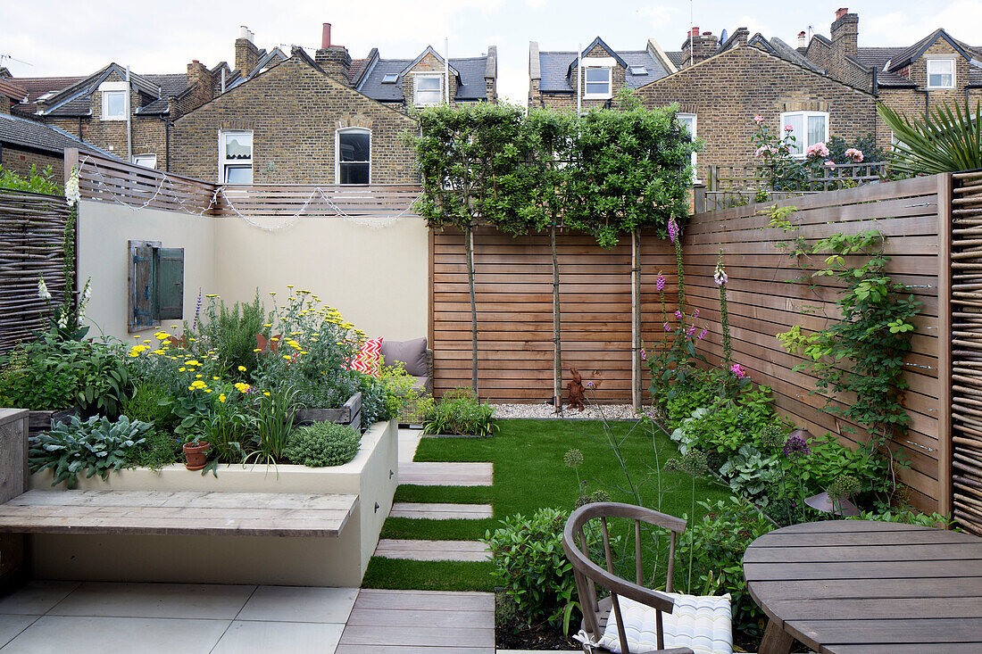 Raised beds and flowering plants in urban courtyard garden of London home, England, UK