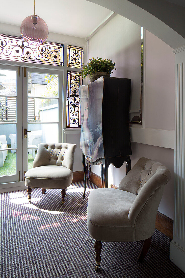 Pair of buttoned beige chairs with vintage cabinet in London townhouse   England   UK