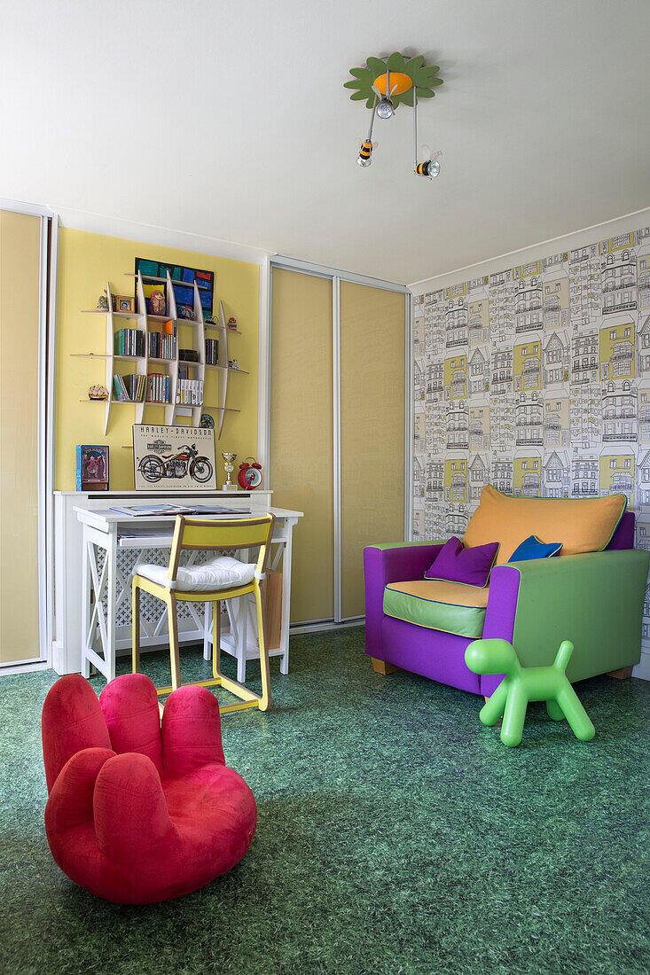 Desk and chair with colourful armchair and red floor seat in child's rom of London townhouse   England   UK