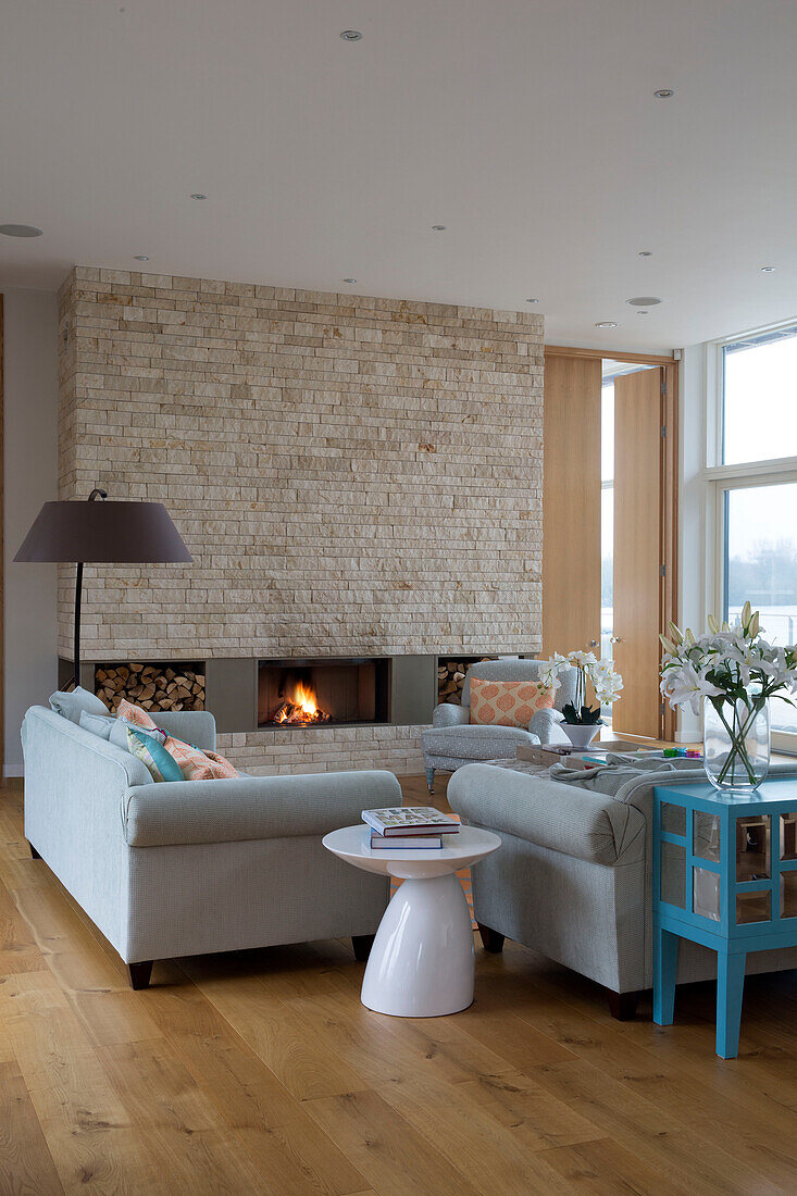 Hellgraue Sofas mit Beistelltisch und freiliegender Steinmauer in einem Haus in Lechlade, Gloucestershire, England, UK