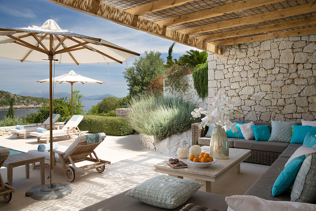 Shaded seating area at poolside with parasols in villa in the Aegean sea Ithaca Greece