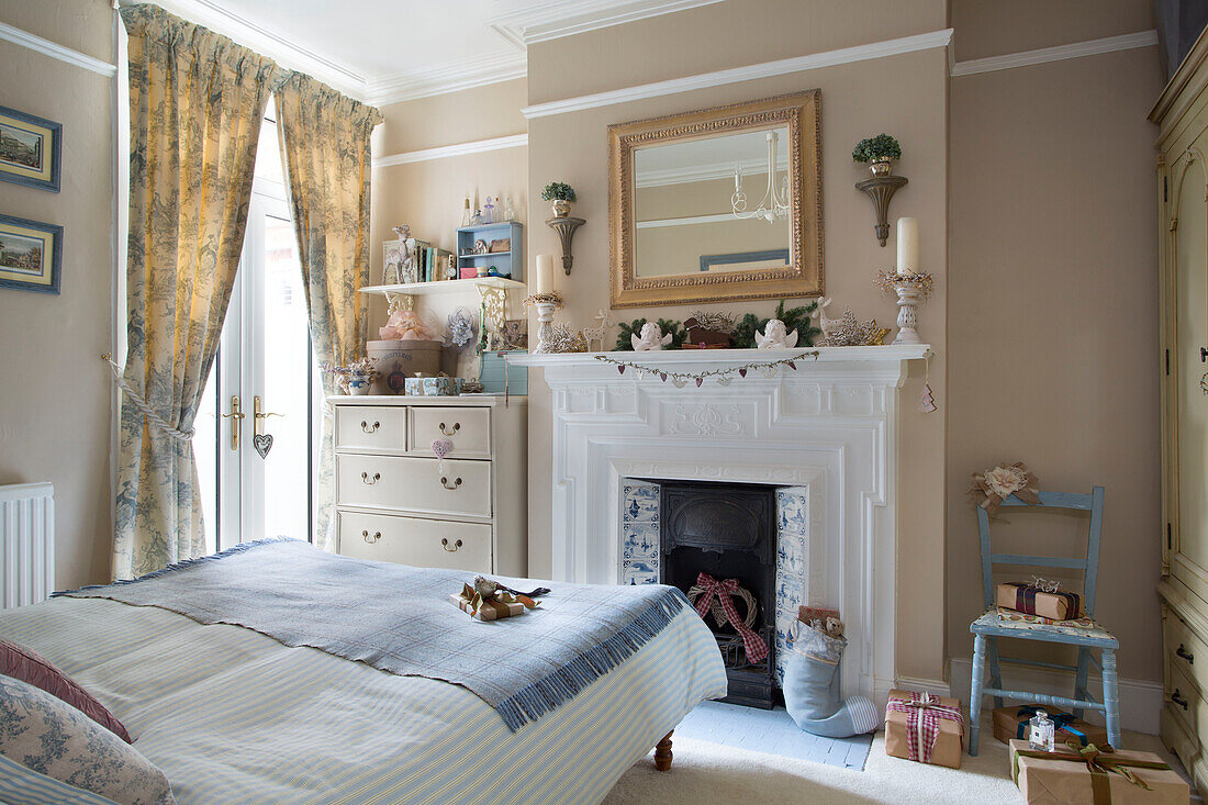 Mirror above painted fireplace in bedroom of London home England UK