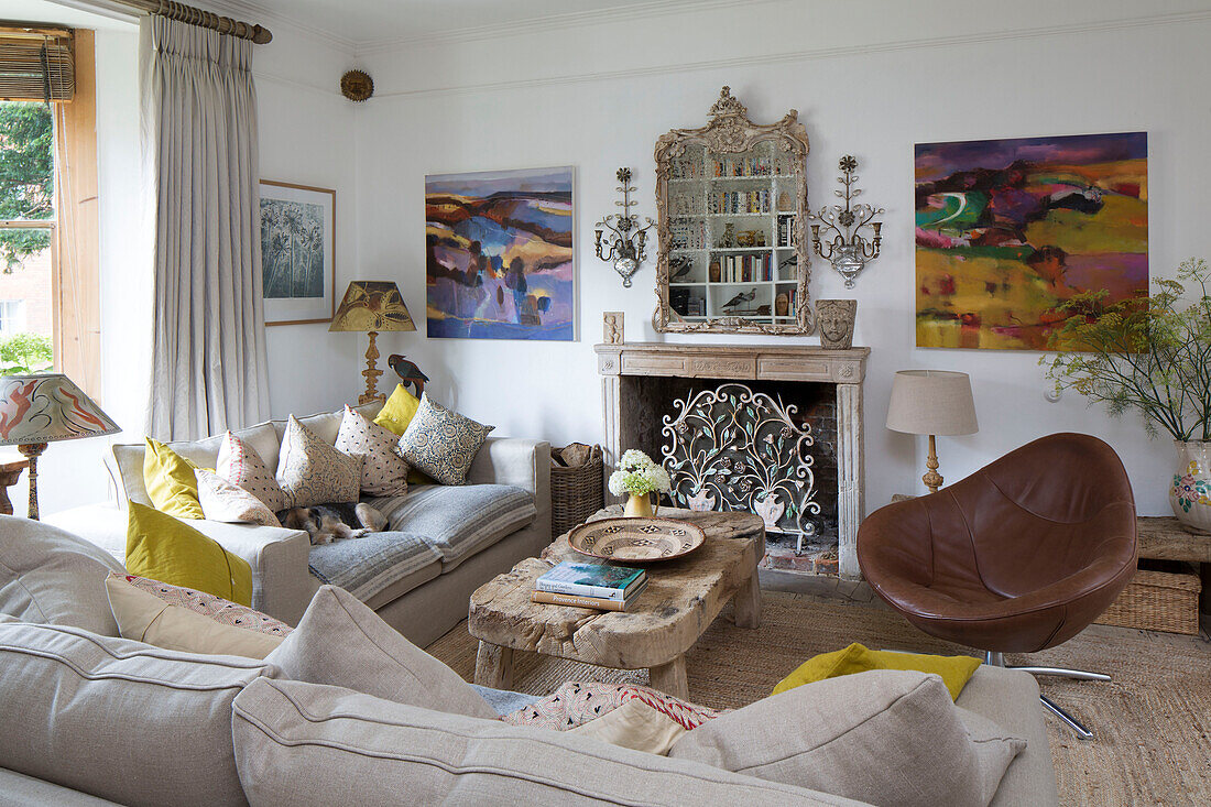 brown leather armchair with wooden coffee table and sofas with yellow cushions in Arundel home West Sussex England UK