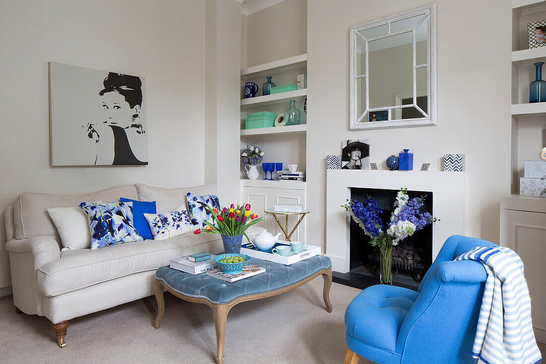 Cut tulips on ottoman footstool with sofa and canvas of Audrey Hepburn in London townhouse UK