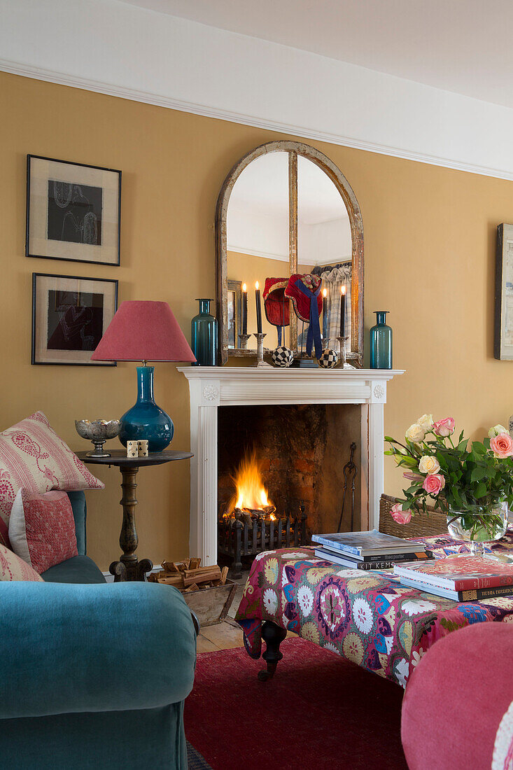 Crochet cover on ottoman in front of lit fire in living room of Sussex home England UK