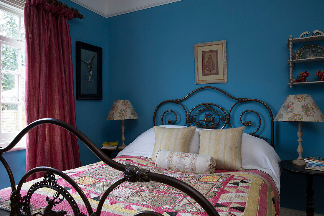 Patchwork cover on metal framed bed in blue bedroom of Sussex home England UK