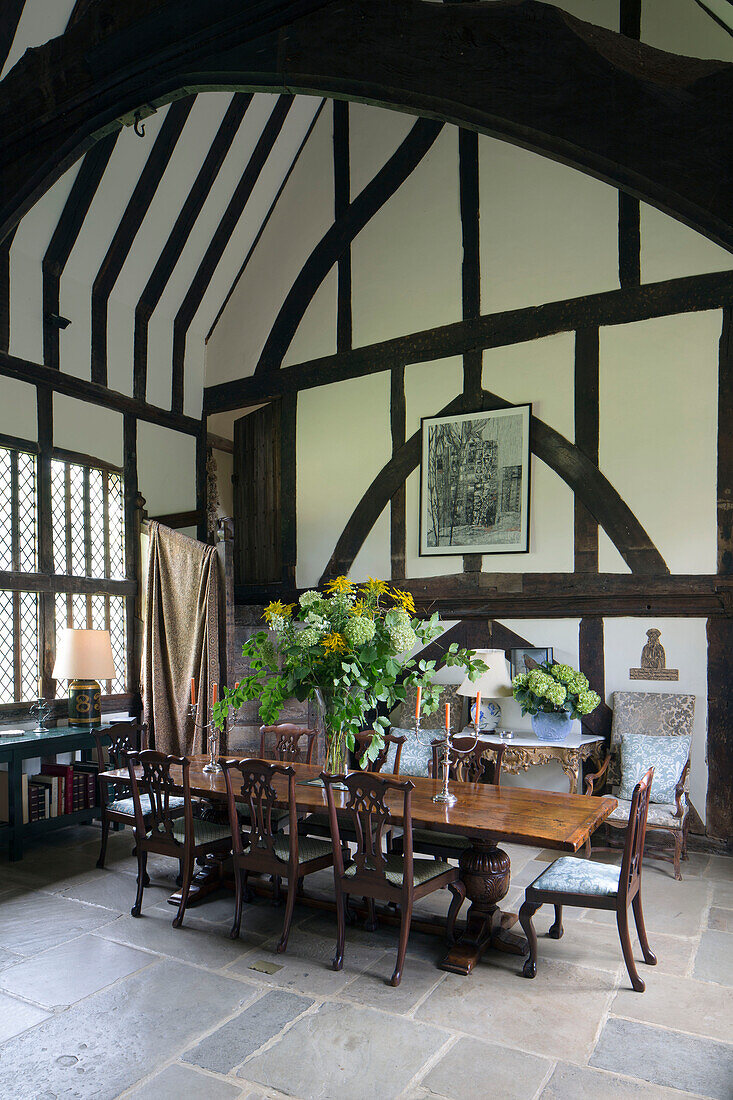 Large flower arrangement on wooden dining table in timber framed Kent farmhouse UK