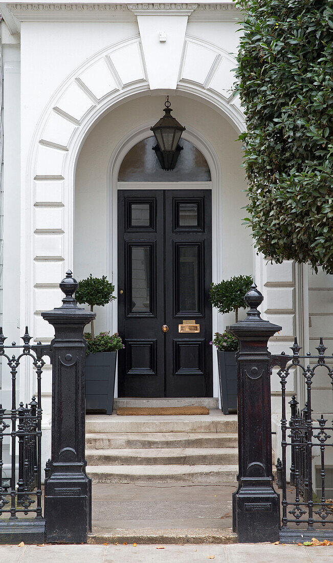 Classic black front door and gateposts at exterior of London townhouse UK