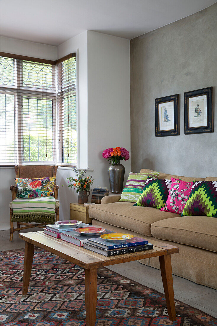 Vintage coffee table in living room with bright scatter cushions in London home England UK