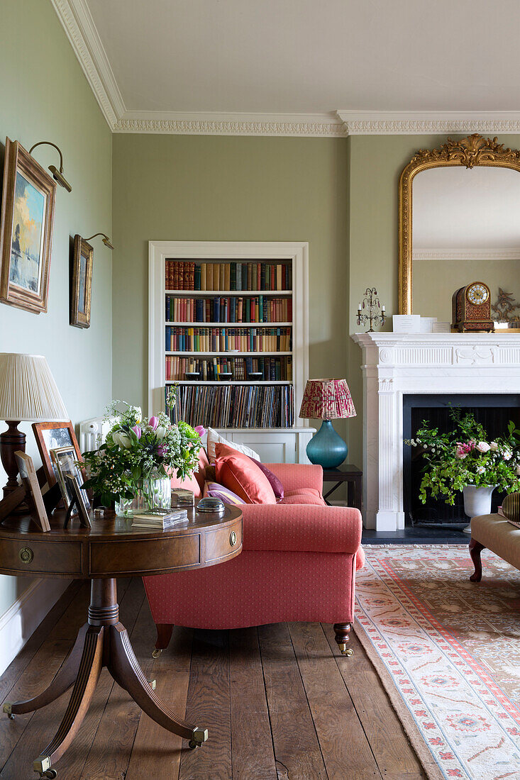 Antiker Tisch und Sofa mit eingelassenem Bücherregal in einem unter Denkmalschutz stehenden georgianischen Landhaus in Shropshire, England UK