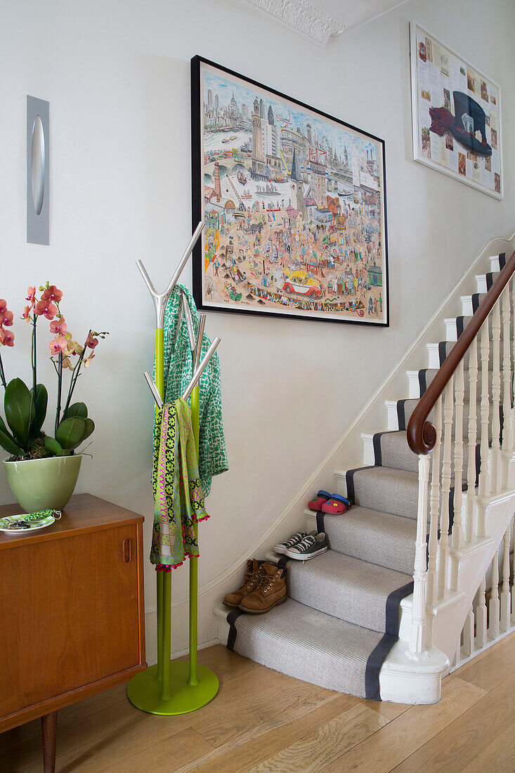 Lime green hat stand and framed artwork with shoes on staircase in London townhouse England UK