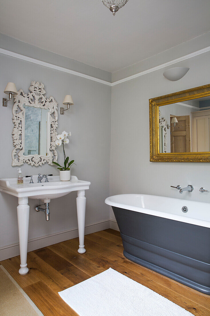 Vergoldeter Spiegel über einer grauen, freistehenden Badewanne in einem Haus in Gloucestershire, England