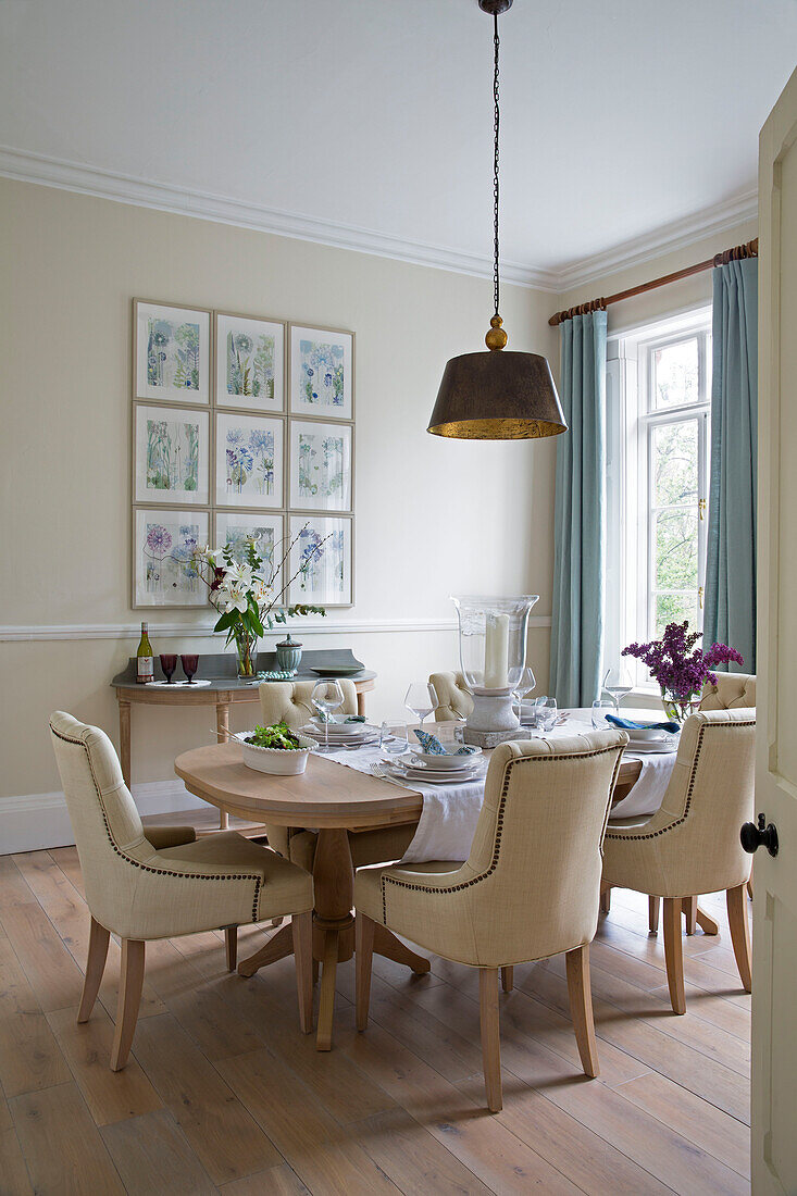 Cream upholstered dining chairs with brass pendant light in Worcestershire home England UK