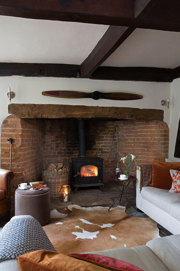 Lit wood burning stove in exposed brick fireplace of Worcestershire home England UK