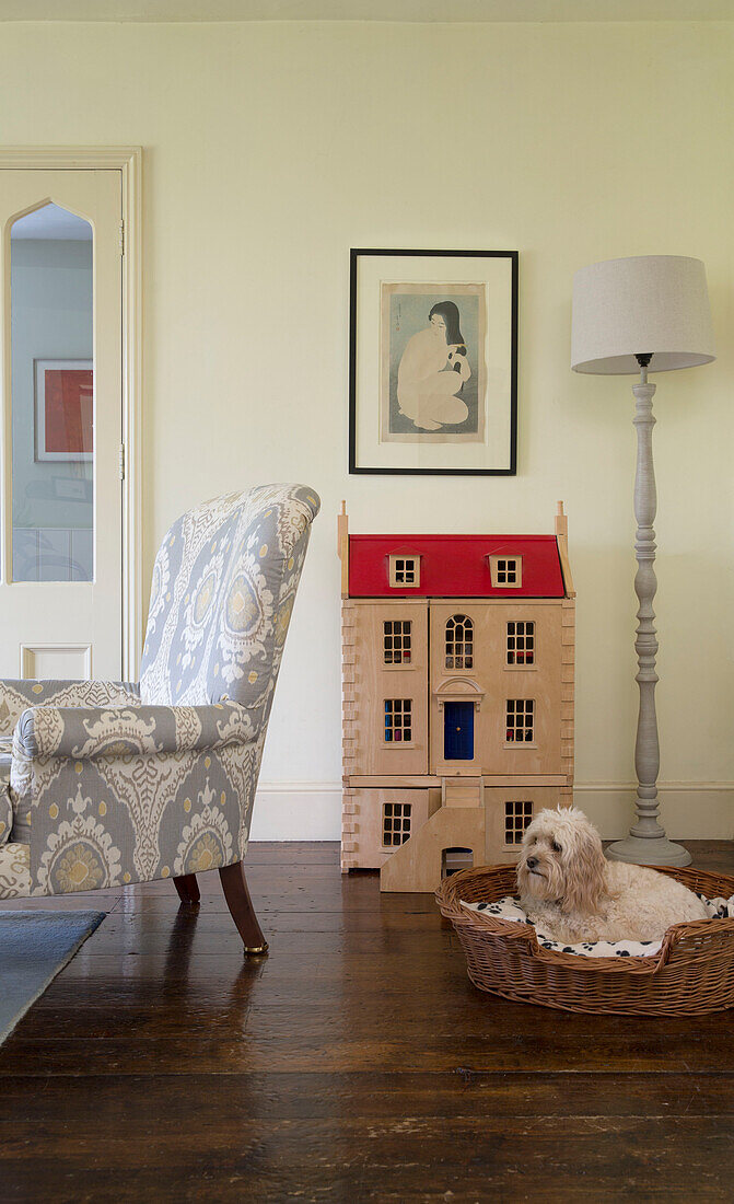 Upcycelter Sessel mit Hund im Puppenkorb und Stehlampe in einem Bauernhaus in Gloucestershire, England UK