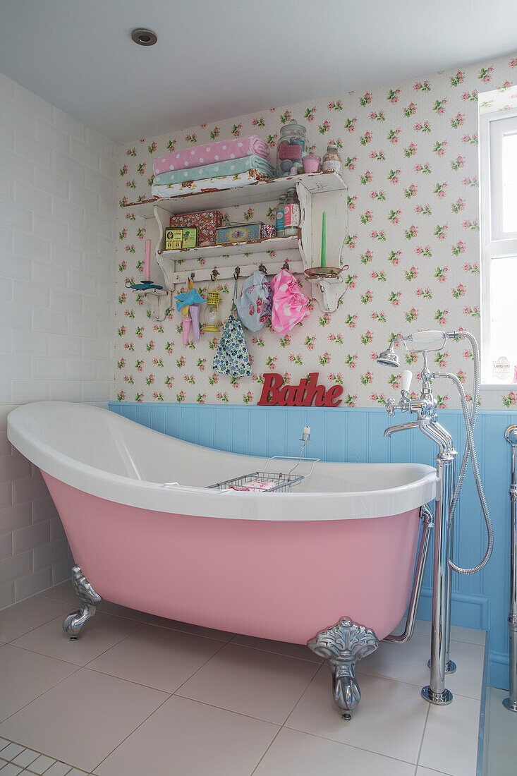 Retro- style pink freestanding bath below shelving in Victorian terraced cottage Kidderminster Worcestershire England UK