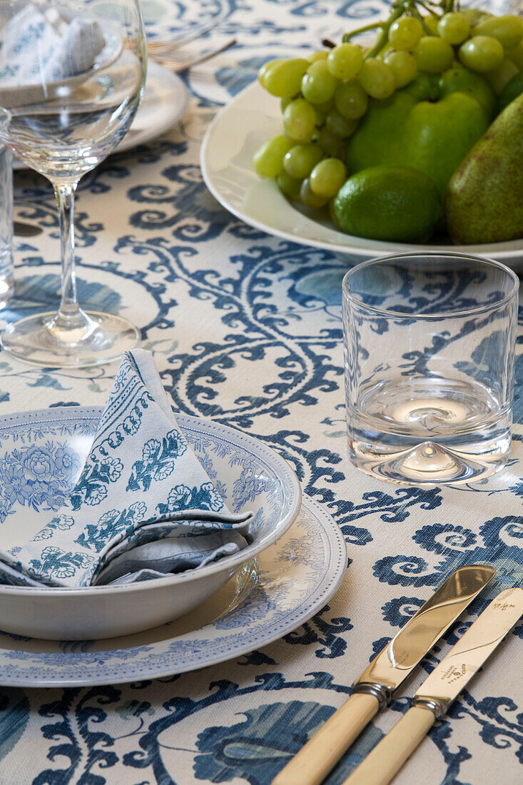 Blue and white napkin in bowl with cutlery and grapes on dining table in Gloucestershire cottage UK