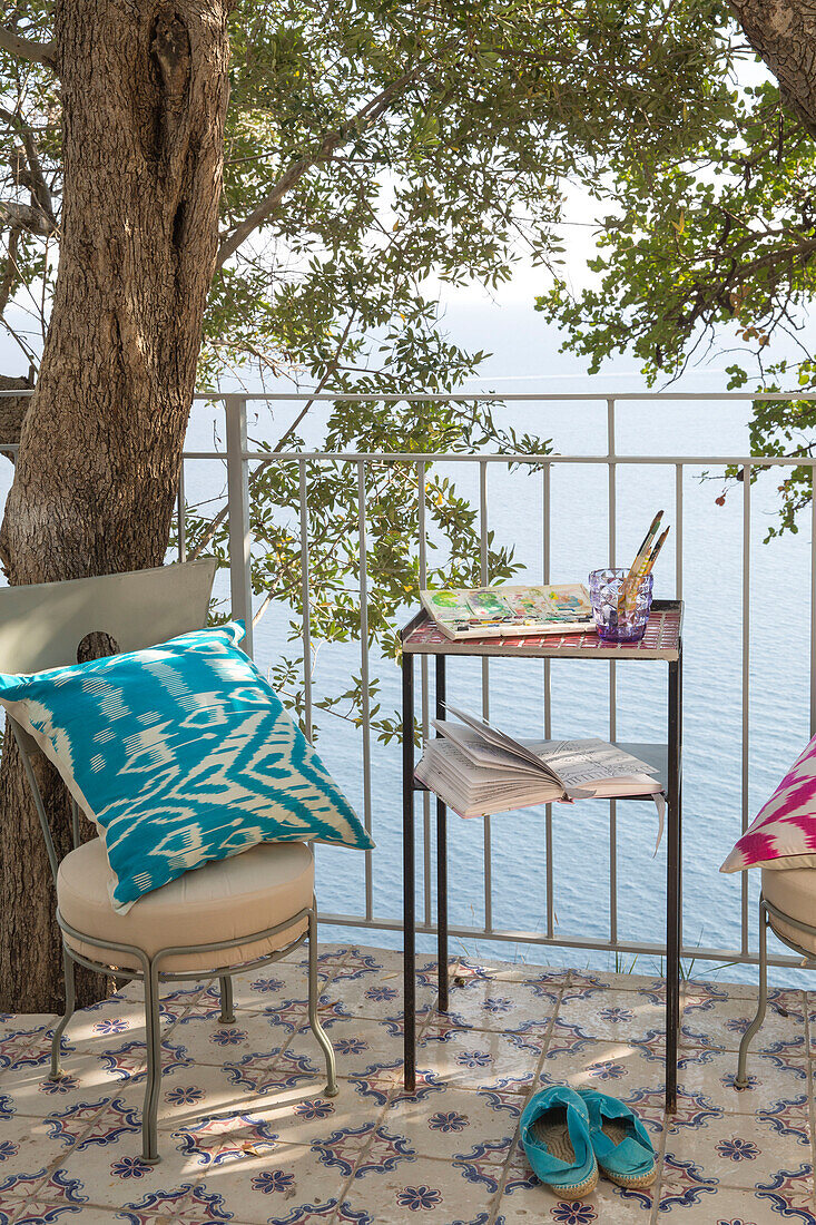 Turquoise cushion and espadrilles on tiled balcony terrace of 970s villa on South West Italian coast
