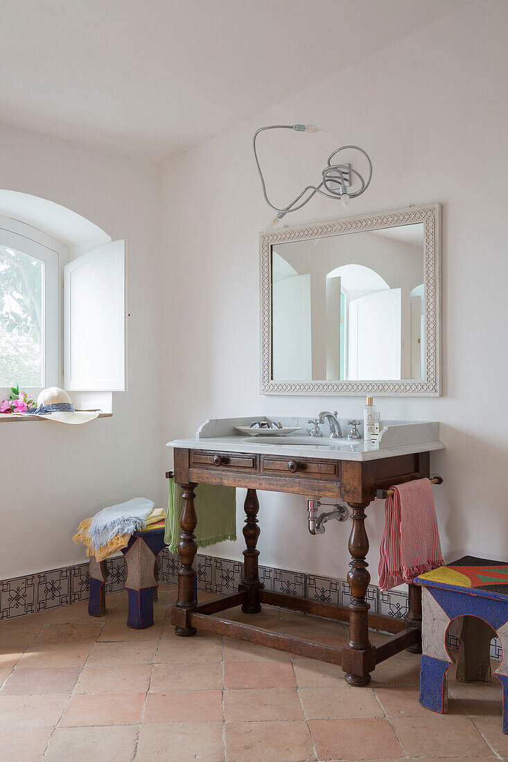 Large mirror above wooden wash stand at window in Italian villa Amalfi Southwest
