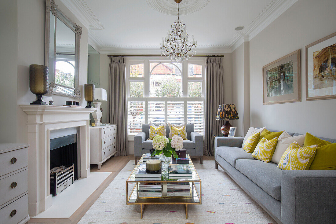 Yellow cushions on grey sofas with vintage coffee table in living room of London townhouse UK