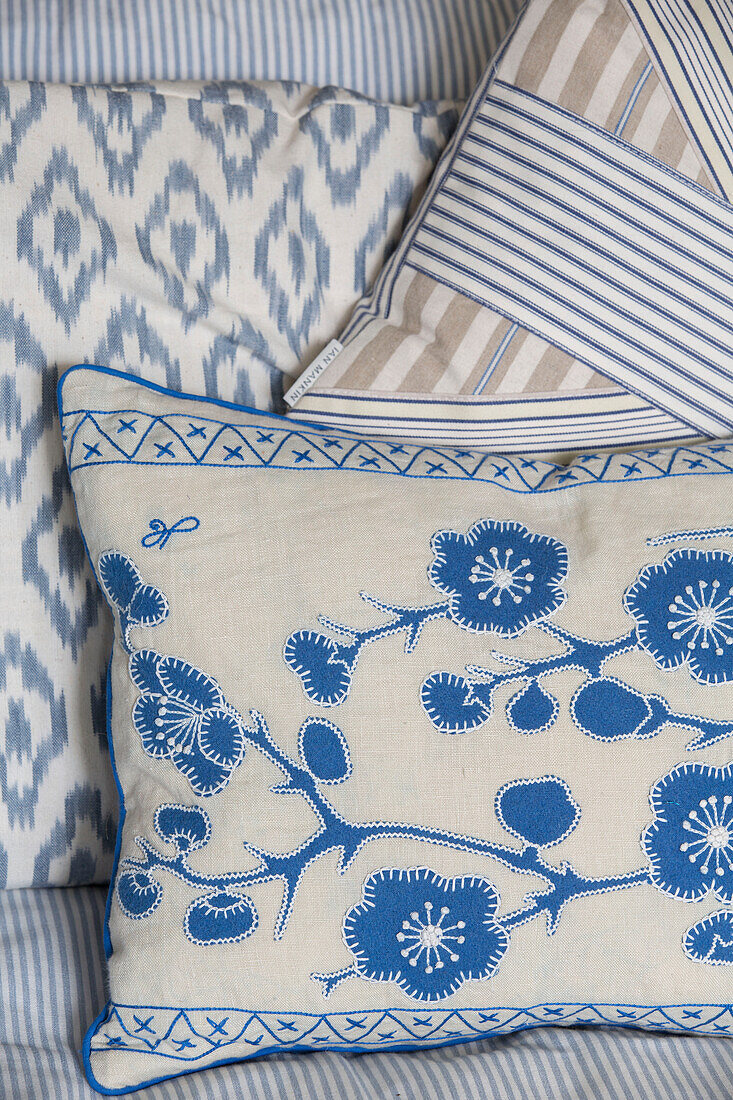 Patterned blue cushions on sofa in Victorian terrace house South London UK