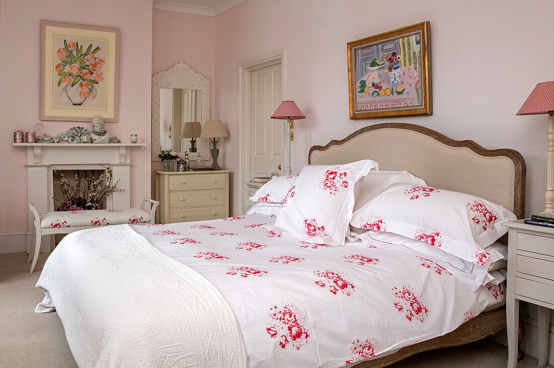 Rote geblümte Bettdecke und Kissen auf einem Doppelbett im rosa Schlafzimmer eines viktorianischen Reihenhauses in South London UK